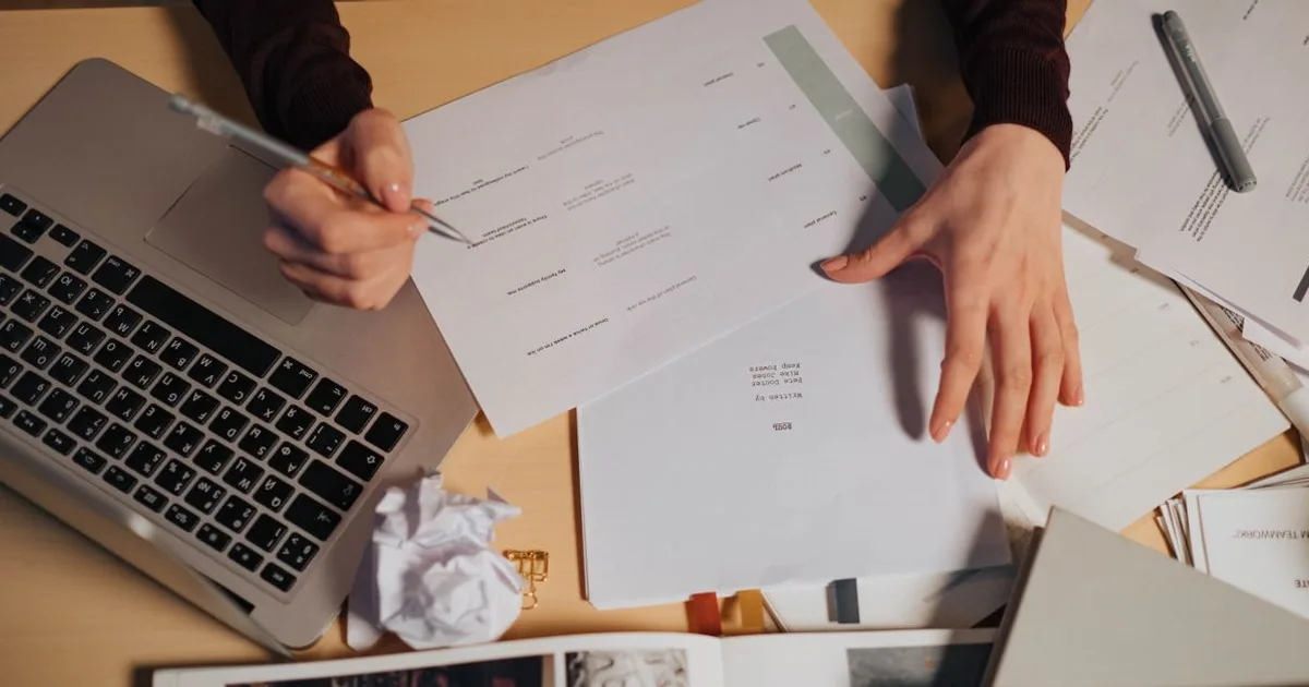Person comparing official exam outline PDF with flashcards on a laptop