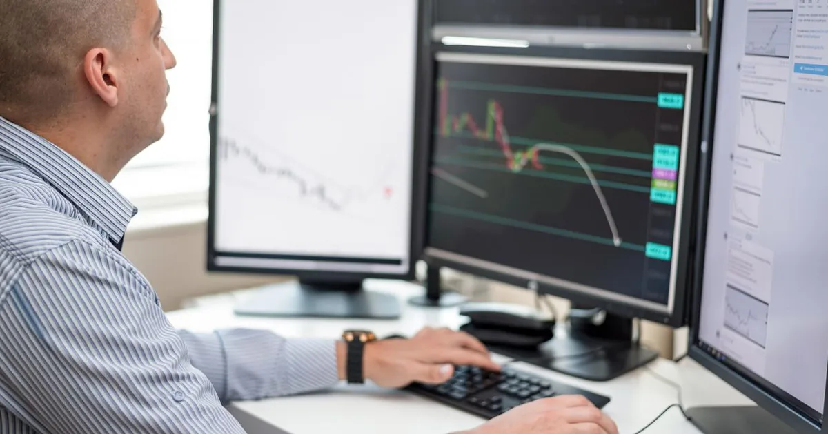 Finance professional reviewing charts and risk analytics on dual monitors