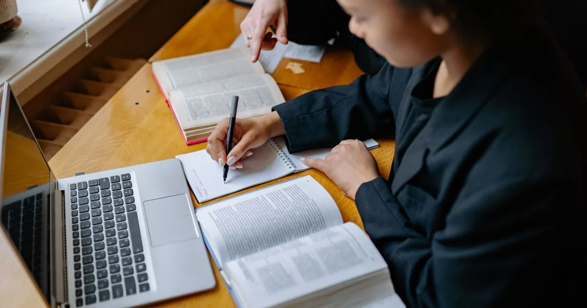 Student reading a green building handbook and taking notes at a desk