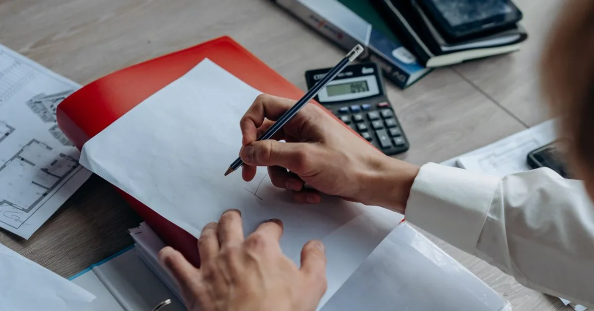 Quantity surveyor reviewing cost plans and floor drawings at a desk